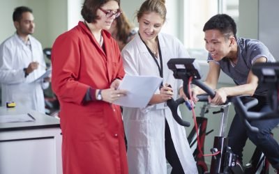 Healthcare professionals discussing over paperwork by an exercise bike in a modern clinic